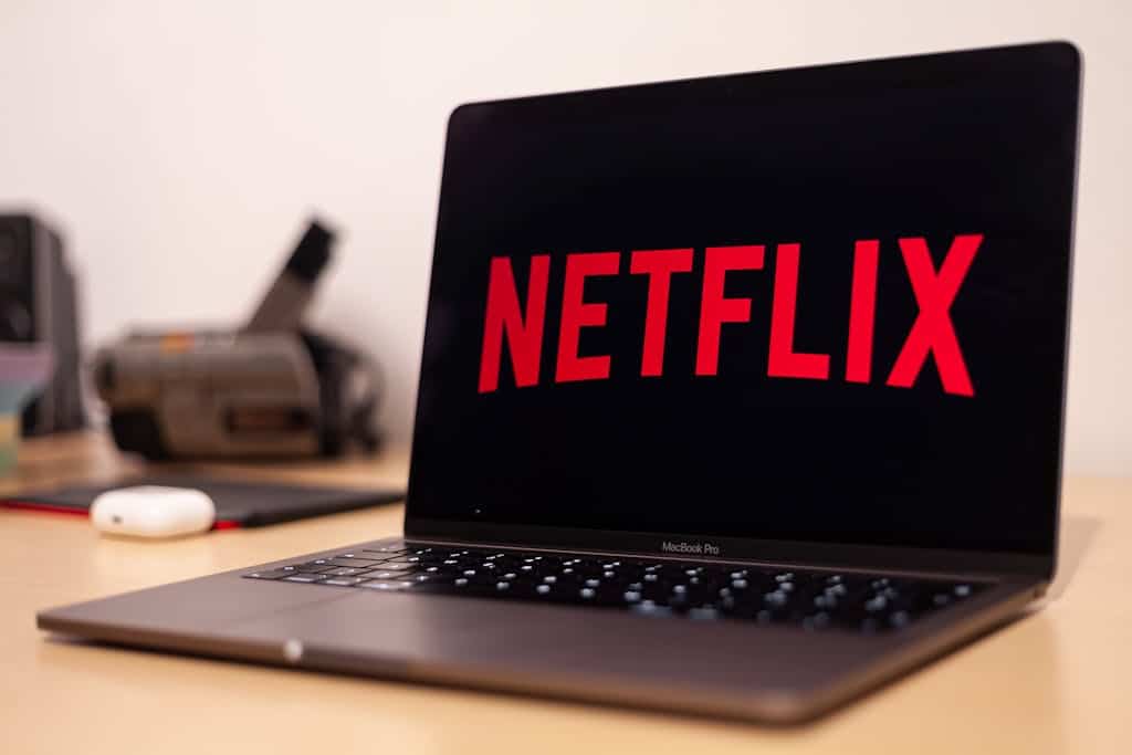 Close-up of a MacBook Pro showing Netflix on the screen in a modern workspace.